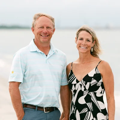 Russell Davis and his wife smiling together outdoors by the water.
